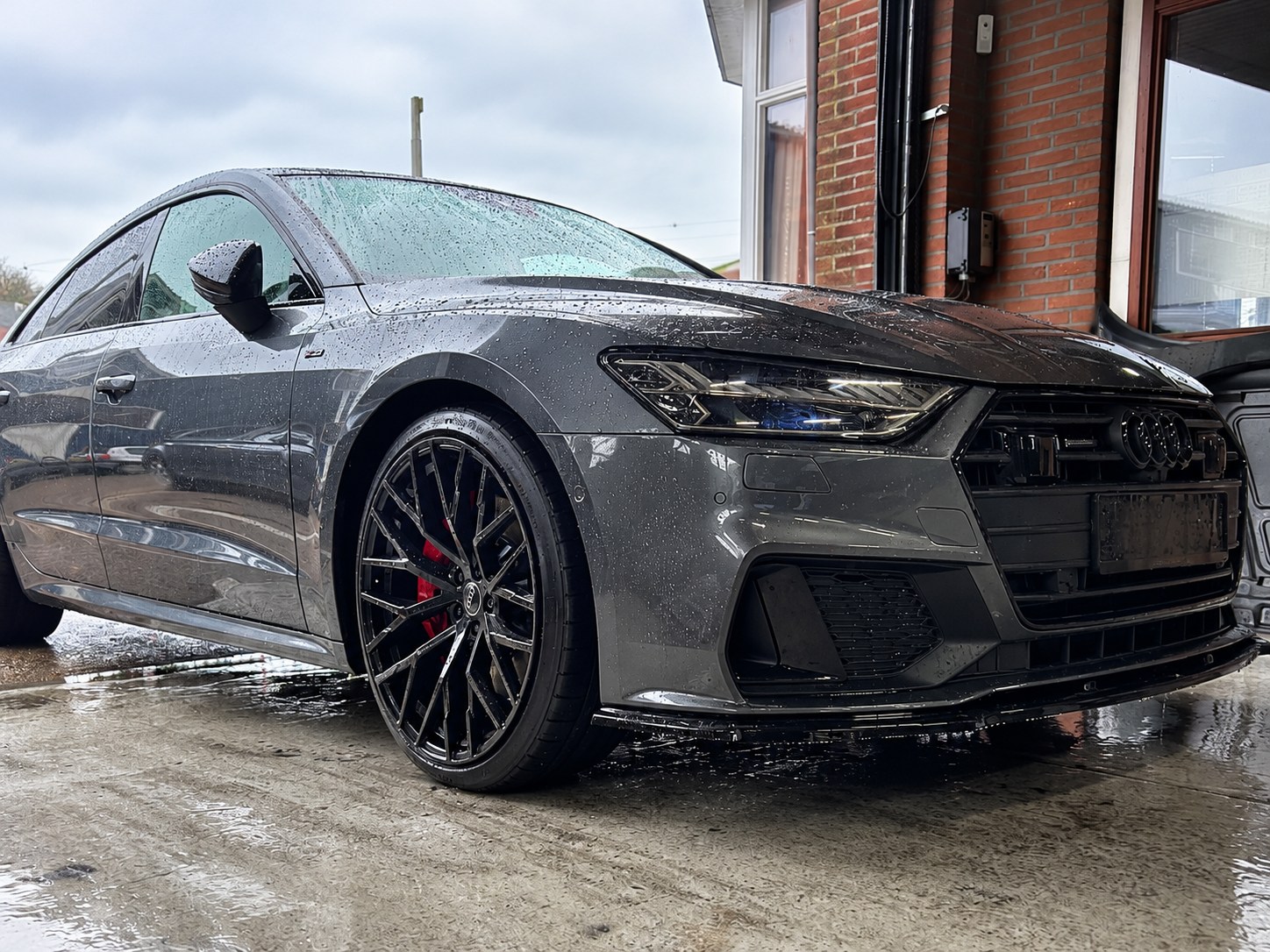 Grijze Audi op een natte werkplaatsvloer